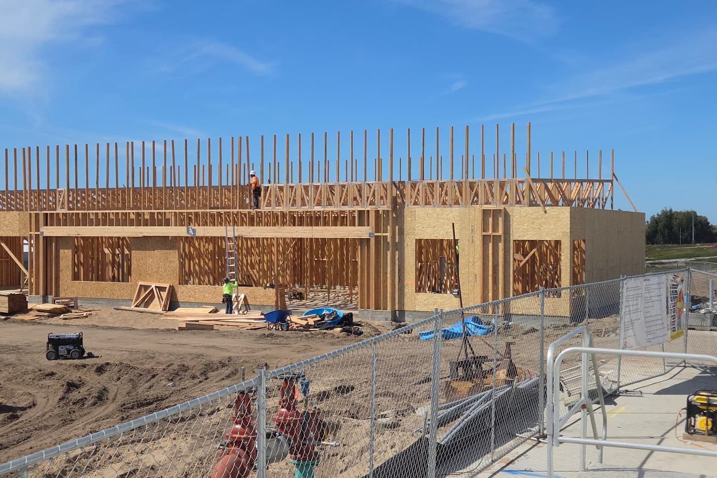 Wood-framed commercial building under construction against a blue sky