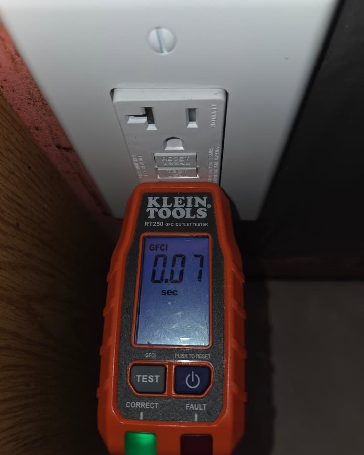 Plug-in outlet tester in a wall receptacle showing a GFCI trip time reading